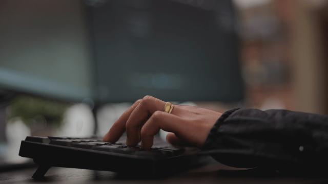 Two monitors which are connected with a Lenovo Dock and a hand writing on the keyboard