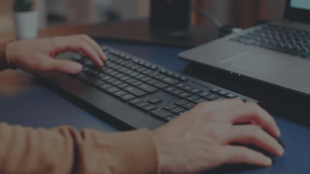 An employee sitting at their workstation and using various HP products.